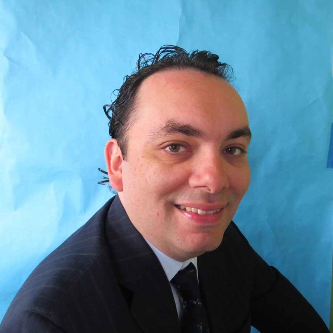 A man in a suit and tie smiling for the camera.