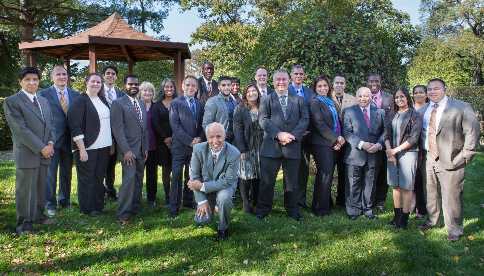 A group of people in suits and ties standing on top of grass.